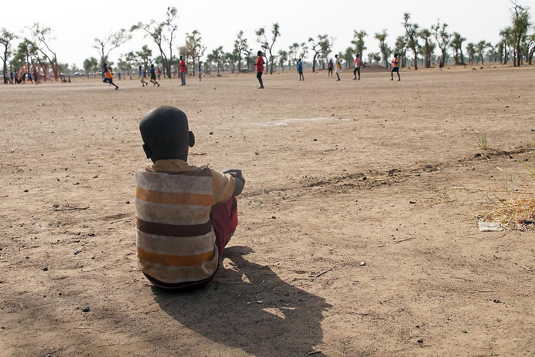 Ein Junge sieht einem Fussballspiel in einem Kinderzentrum zu. Gendrassa-Flüchtlingslager, Südsudan. Foto: LWB/ C. Kästner