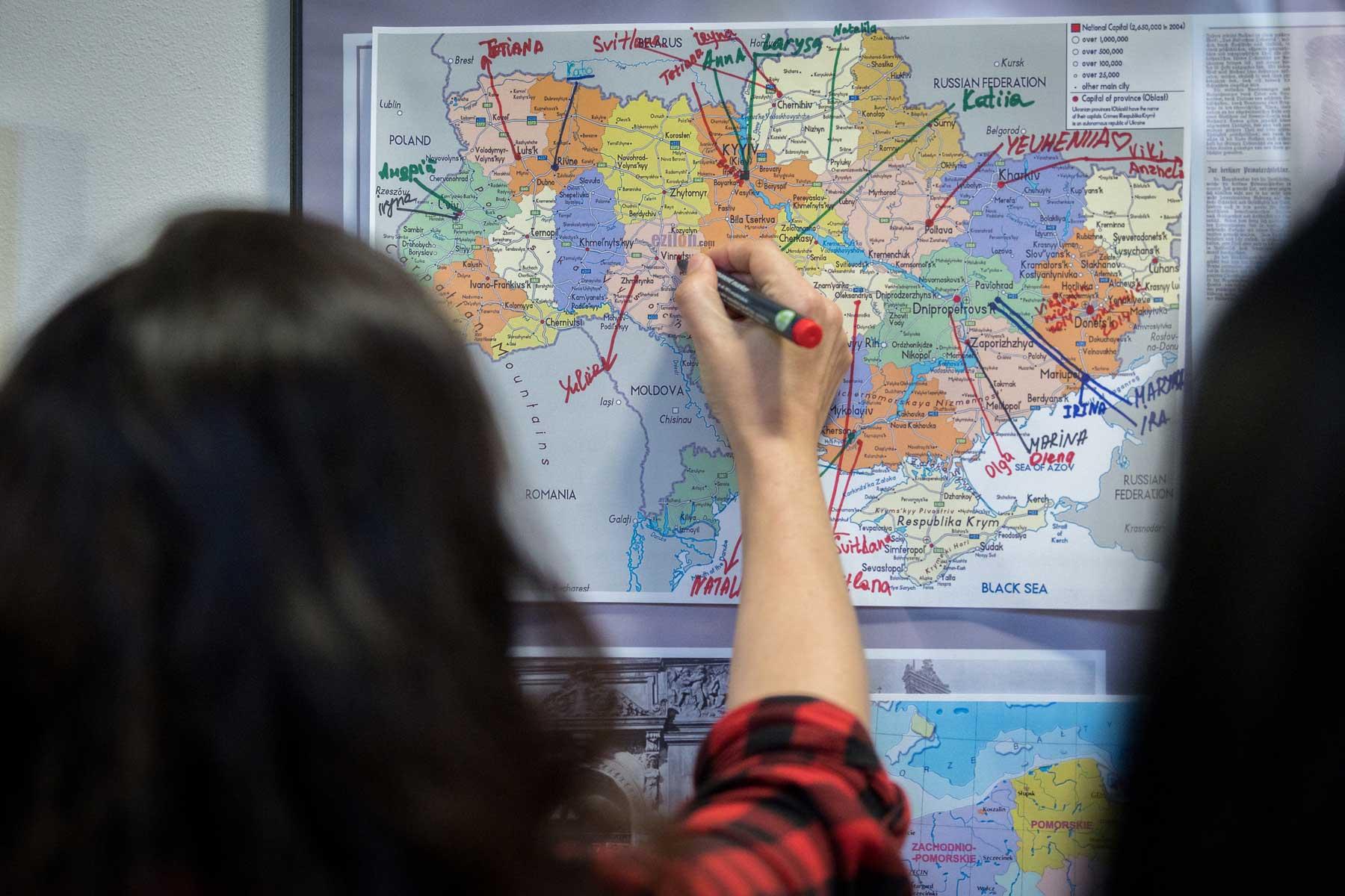 Eine Frau markiert auf einer Landkarte, aus welchem Teil der Ukraine sie stammt. Mitarbeitende des LWB - die meisten von ihnen Flüchtlinge aus der Ukraine - nahmen an einer Schulung in Beuthen, Polen, teil. Foto: LWB/Albin Hillert
