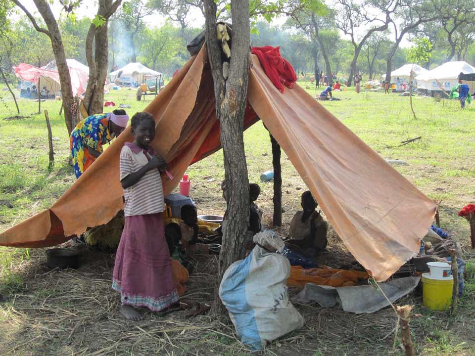 Eine kürzlich im Flüchtlingslager Yusuf Batil in der Provinz Upper Nile angekommene Familie richtet sich bis ihr ein Zelt zugewiesen wird in einer provisorischen Unterkunft ein. © LWB/M. Retief