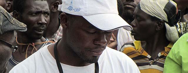 LWF team member Patrick Kalubi examines a list of names at a food distribution center in Goma, DRC. Â© LWF DRC/Fred Otieno