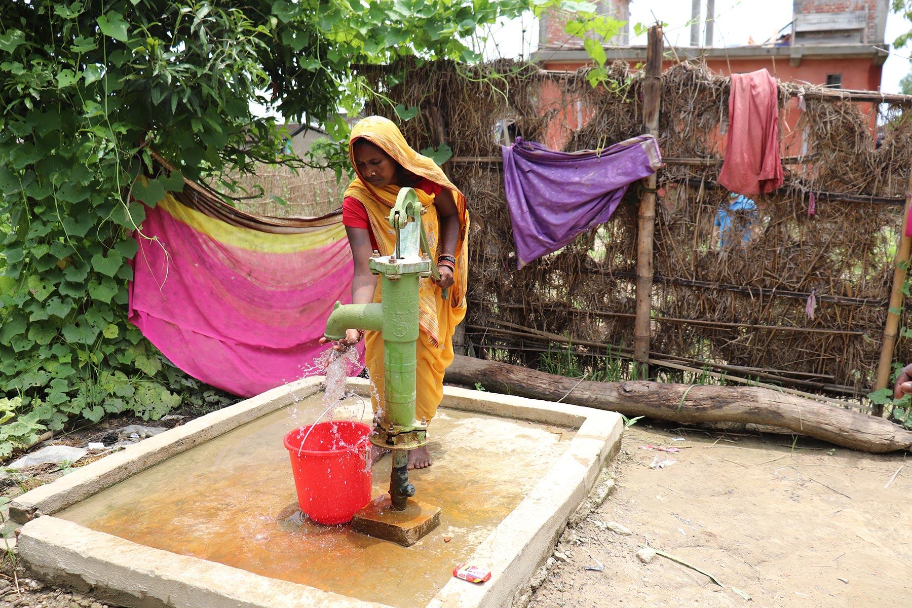 Ms. Rohini Devi Paswan, a resident of Dhanusa, drawing water from a newly constructed hand pump â Photo credit: Suman Rai/LCWS