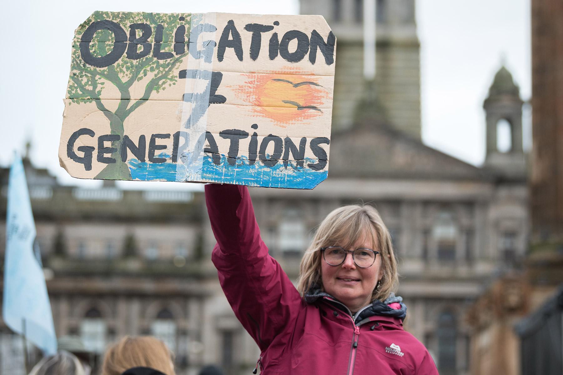 Kathrin Hall holds a sign at an interfaith vigil held at George Square on the opening day of COP26 in Glasgow, Scotland. Photo: LWF/Albin Hillert