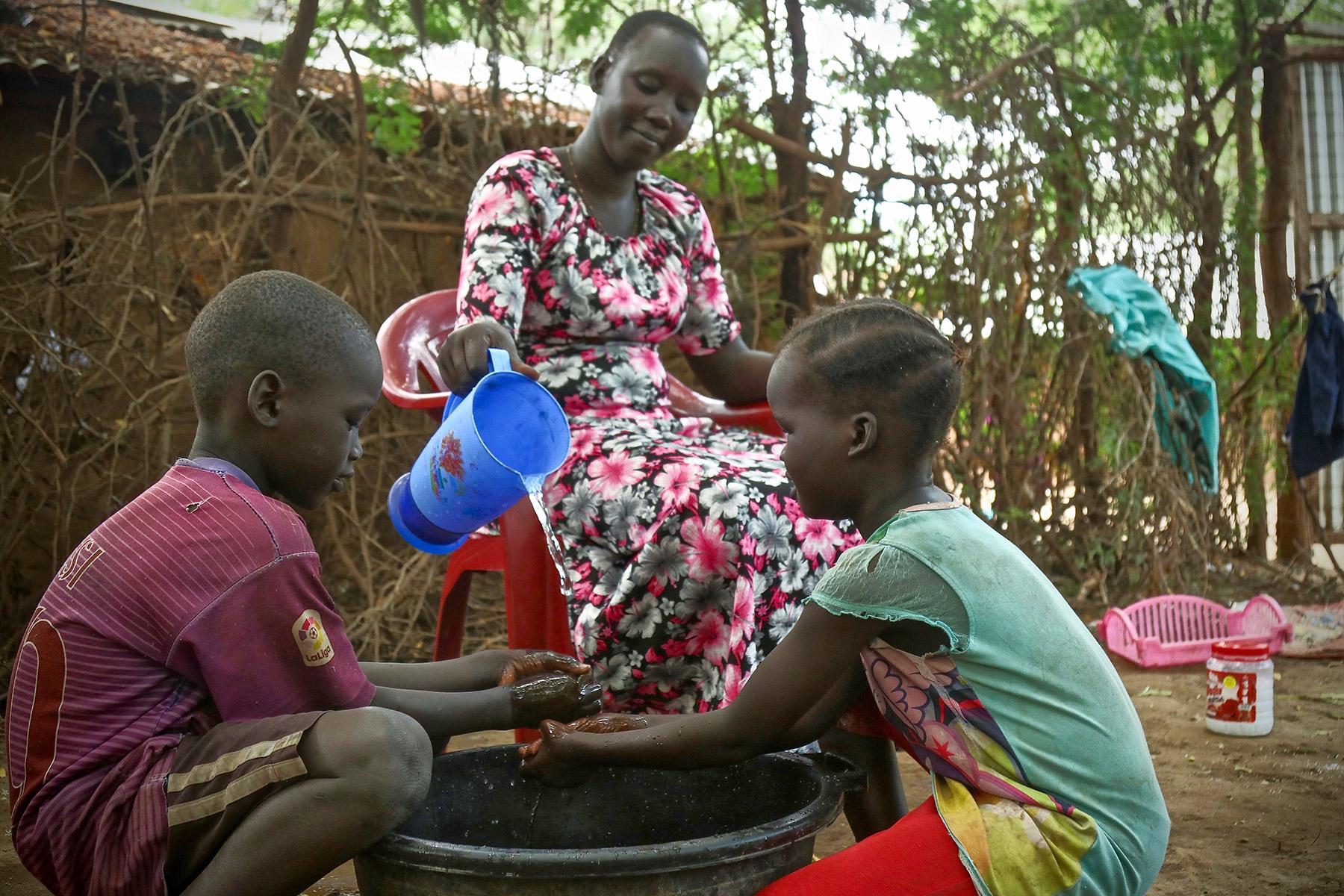 A woman washes her childrenâs hands in Kakuma refugee camp, Kenya. LWF has reinforced hygiene education to prevent a spread of COVID-19 in the camp. Photo: LWF/ P. Omagwa