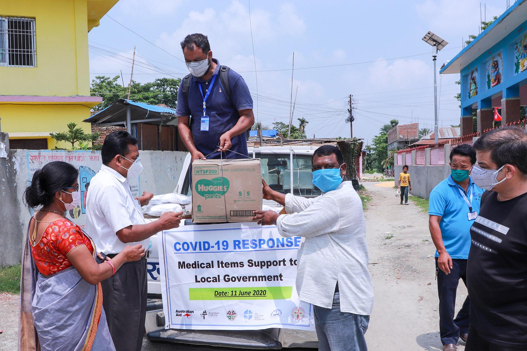 Pfarrer Joseph Soren (rechts) überreicht Pakete mit medizinischen Artikeln und Hygienesets an die Verantwortlichen der ländlichen Gemeinde Jahada im Bezirk Morang im Osten Nepals. Foto: LCWS/Suman Rai
