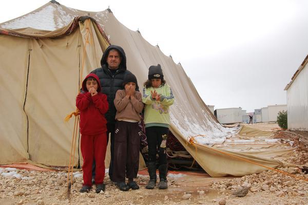 A street leader with his children in front of a half collapsed tent which is used as a Mosque. Photo: LWF/ J. Pfattner