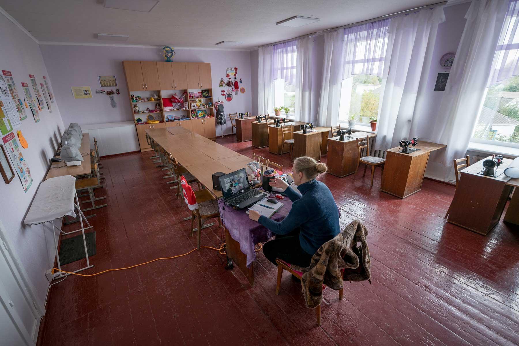 Teacher Natalia Koval leads an online class in textile handiwork at the Ichnya school of Vasilchenko in the Ichnya municipality of Chernihiv Oblast, Ukraine. The school is currently empty of its students, with classes taught online only until secure bomb shelters can be restored at the school. All photos: LWF/Albin Hillert