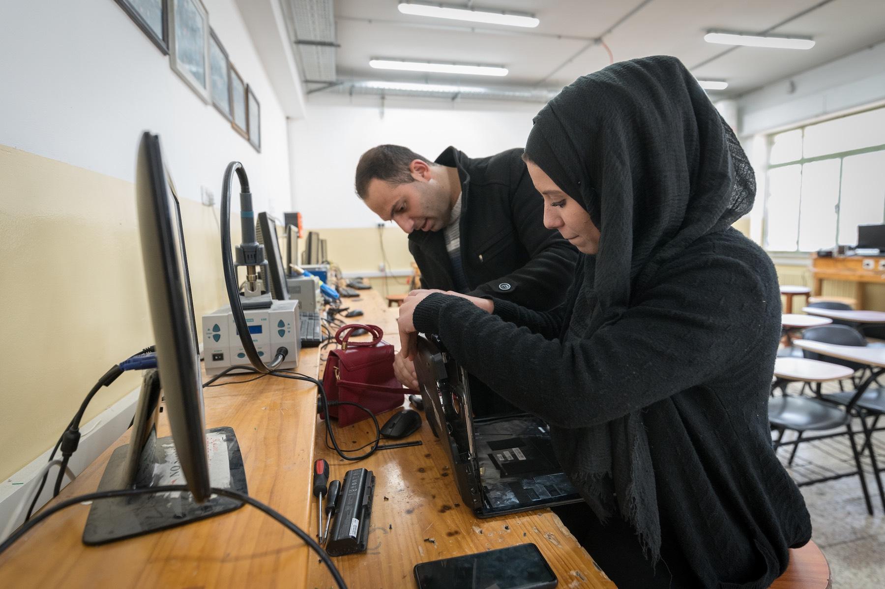 21 January 2023, Ramallah, Palestine: 19-year-old telecommunications student Reham Rajh (right) from Ramallah is at work during a class taught by Anas Shtaya (left) at the Lutheran World Federation’s Vocational Training Centre in Ramallah. The centre currently hosts 141 students across eight different training programmes. This school year, 85 of the students are female. Photo: LWF/ Albin Hillert
