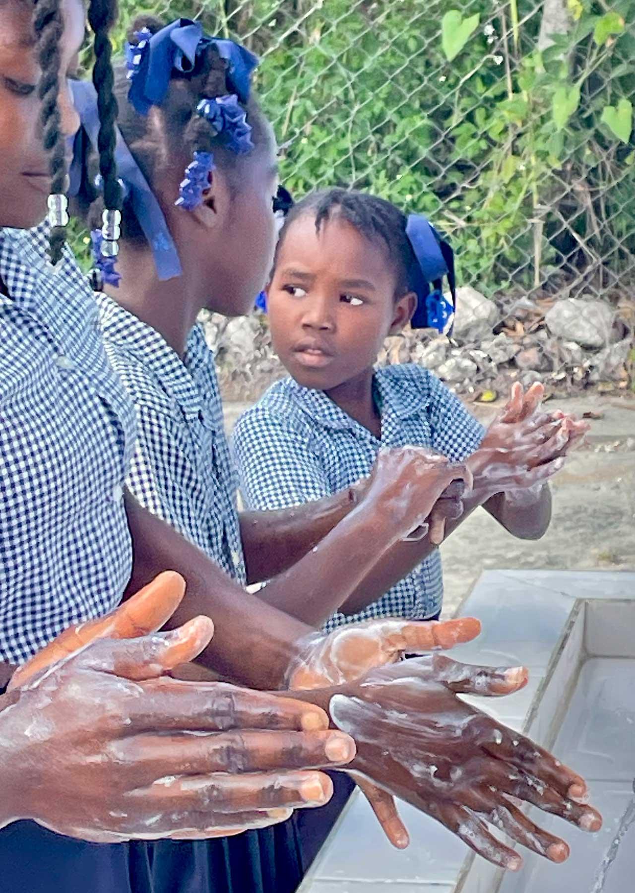 Children wash their hands at Legere school in Cavillon. LWF and partners installed water and sanitation in the school – before , the children had to walk one hour to find safe drinking water. Photo: LWF/ M. French