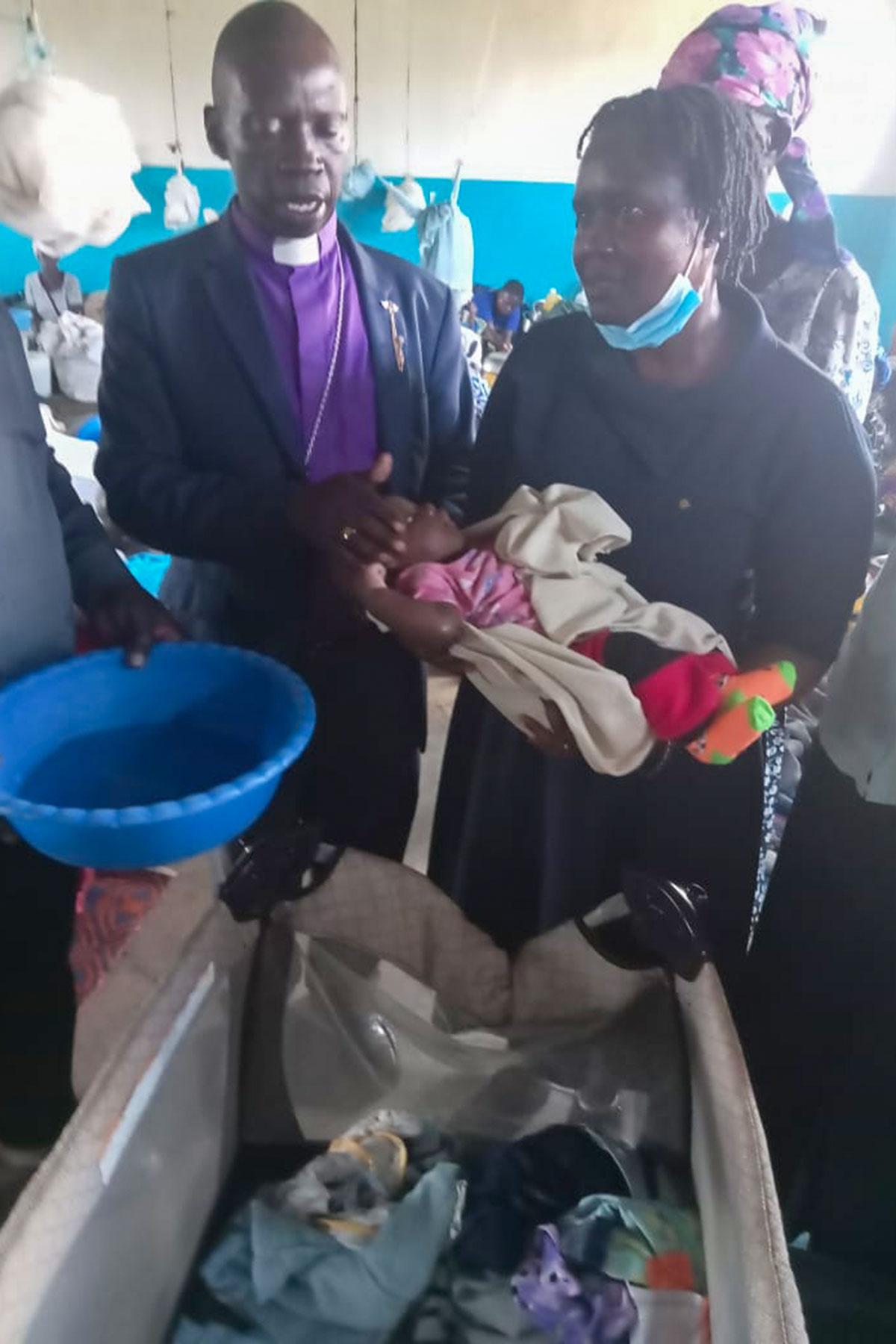 Bischof Titus Okoda von der Lake-Diözese der ELKK tauft ein Kind in Lager Ombaka, in dem 600 Familien nach der Überflutung ihres Dorfs Zuflucht gefunden haben