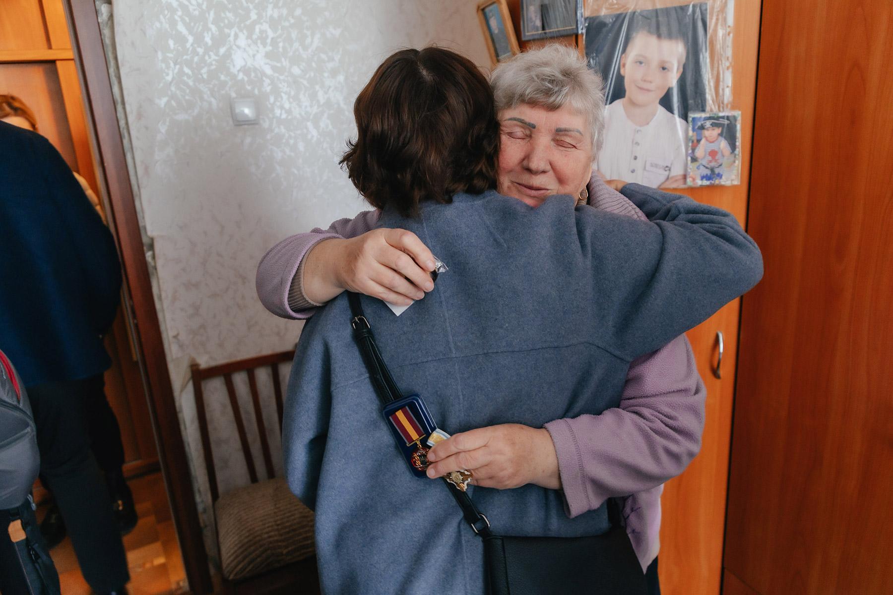 Maria Ivaninvna from Kharkiv hugs LWF General Secretary Rev. Dr Anne Burghardt on the solidarity visit on 14 May 2024. Ivanivna's apartment was hit by a missile in 2022 and rehabiliated by LWF. Behind her are the pictures of her sons, who are fighting in the army, and her grandson. Photo: LWF/ Anatolyi Nazarenko
