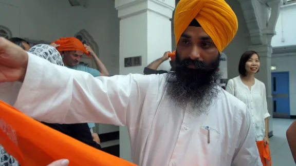 Gurmel Singh from the Sikh Temple in Hong Kong handing out headscarves to participants at the interfaith consultation in Hong Kong. Photo: LWF/I. Benesch 