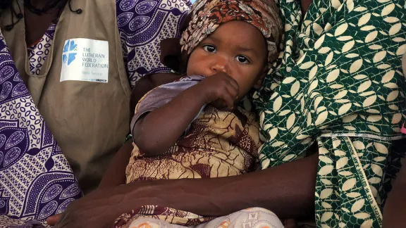 A child is cradled by her mother during one of the meetings of the peace committee in Borgop camp, Cameroon. The committee mediates conflicts involving the refugees, and has also managed to reduce domestic violence and violence against children. Photo: LWF/ C. KÃ¤stner