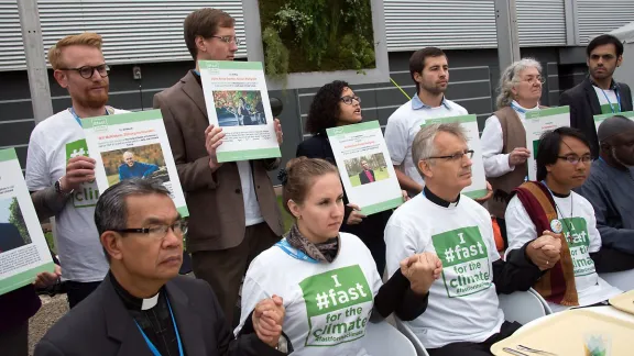 Eine interreligiöse Gruppe vor leeren Tablets bei einer Demonstration während des Klimagipfels in Paris 2015. Foto: LWB/Ryan Rodrick Beiler