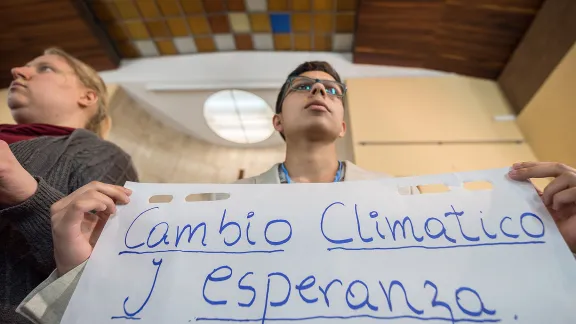 „Cambio Climático y Esperanza" (Klimawandel und Hoffnung) steht auf einem Blatt Papier, das Sebastian Ignacio Muñoz Oyarzo von der Evangelisch-Lutherischen Kirche in Chile als Delegierter des Lutherischen Weltbundes hochhält. Es enthält eine Zusammenfassung der wichtigsten Diskussionspunkte eines interkonfessionellen Dialogs, der am 1. Dezember in Madrid stattgefunden hat. Fotos: LWB/Albin Hillert