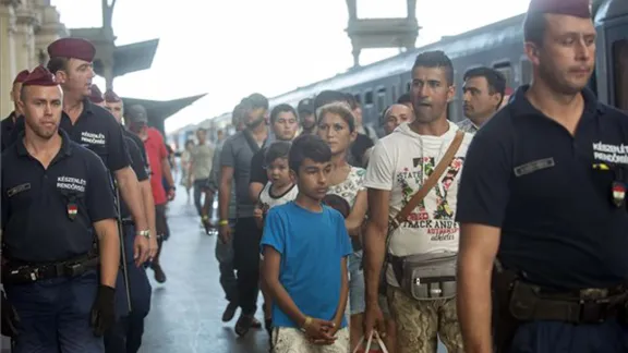 Refugees in Hungary are escorted along a train platform. Photo: MTI