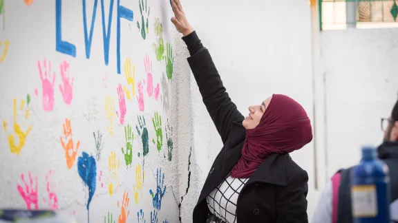 Zarqa, Jordan: Incentive-Based Volunteer Esraa from Jordan paints her handmark on the wall of the Lutheran World Federation community centre in Zarqa. Through a variety of activities, the Lutheran World Federation community centre in Zarqa serves to offer psychosocial support and strengthen social cohesion between Syrian, Iraqi and other refugees in Jordan and their host communities. Photo: LWF/Albin Hillert