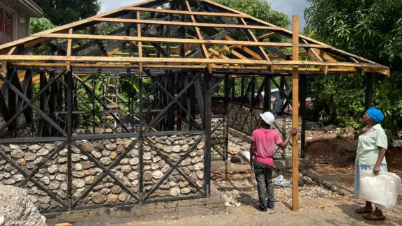 As part of the housing construction project, participants provide rocks, wood and food for the construction workers. Marie Nusia, a project participant, observes the progress on her new hurricane and earthquake resistant home. Photo: LWF Haiti