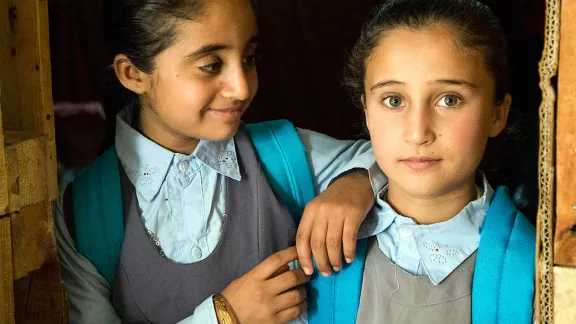 Caption: Shemaa (8) and Bushra (9) getting ready for school. The girls and their family live in a communal shelter with 31 other people. Photo: LWF/ Seivan Salim