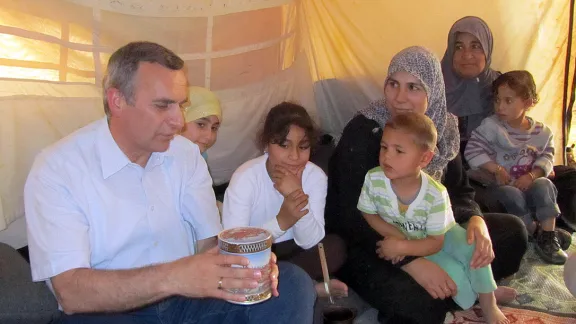 Pfr. Michael Martin schenkt einer syrischen Familie im Flüchtlingslager Za‘atari eine Dose mit Süssigkeiten. Foto: LWB Jordanien/E. Gano