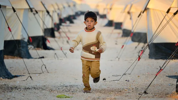 Ein Junge aus dem Zaatari Flüchtlingslager in der Nähe von Mafraq (Jordanien), läuft morgens zwischen den Zeltreihen entlang. Das Lager wurde 2012 eröffnet und beherbergt 20.000 syrische Flüchtlinge. Ihre Zahl steigt weiter an. Foto: Paul Jeffrey/ACT