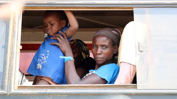 A woman newly arrived from the DRC holds a child as they wait to be moved from the Sebagoro landing site. LWF Uganda is at the frontline of the refugee response. All Photos:  LWF Uganda / S. Nalubega