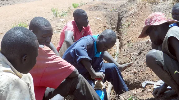 LWF water technicians fix a pipe in Ayilo2 refugee camp, Adjumani district, Uganda. Photo: LWF Uganda