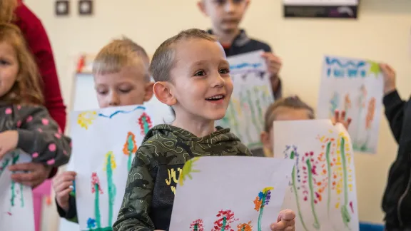 Ein Junge zeigt ein Bild, das er bei der Kinderbetreuung im LWB-Gemeindezentrum gemalt hat