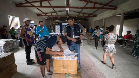 26 October 2023, El Guante, Cedros, Honduras: LWF World Service staff Lucas Reniery Funes Posadas oversees the distribution of goods intended as 'seed capital' offered to returned migrants as part of a program offering them support in starting small-scale businesses to provide for themselves. Photo: LWF/A. Hillert