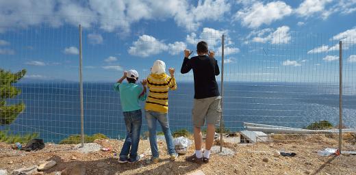  Syrian refugee children at a fence facing the Aegean Sea coast, Greece. Photo: ACT/ Paul Jeffrey 