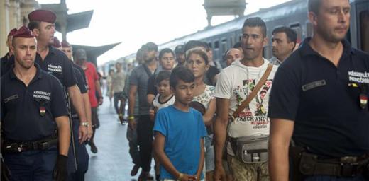 Refugees in Hungary are escorted along a train platform. Photo: MTI