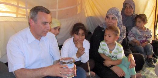 Rev. Michael Martin shares a tin of sweets with a Syrian family at the Zaâatri refugee camp. Photo: LWF Jordan/E. Gano