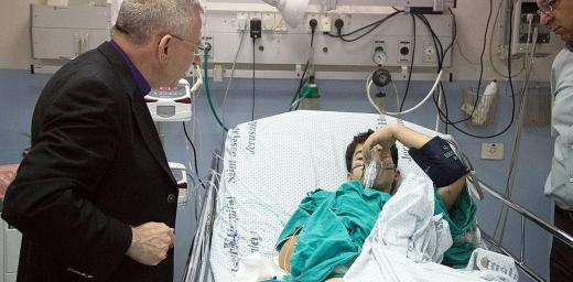 Bishop Munib Younan speaks to an injured boy in the Intensive Care Unit of St. Joseph's Hospital. Photo: D. Hudson/ELCJHL