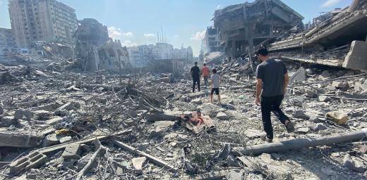 Palestinians walk among the rubble caused by an Israeli airstrike on Gaza City