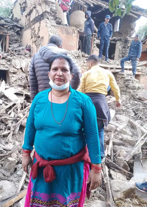 Eine Frau steht vor ihrem eingestürzten Haus. Foto: Bhakta Raj Upadhyay/IP-USSBM Doti