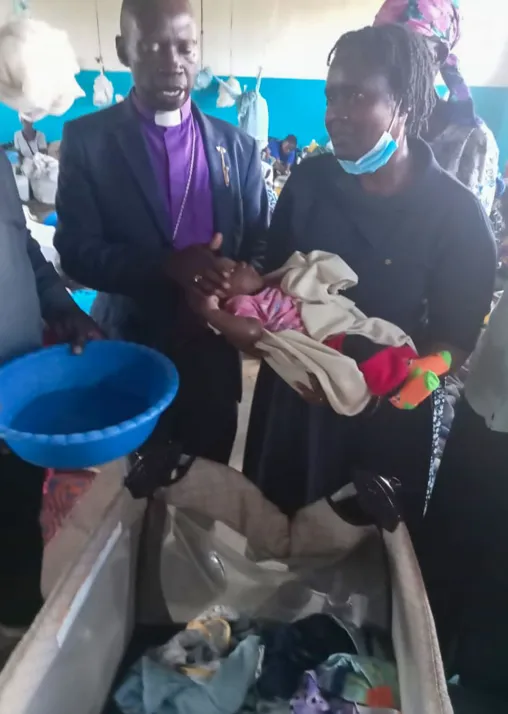 ELCK Lake Diocese Bishop Titus Okoda, baptizing a child at Ombaka camp, where 600 families displaced by flooding were sheltering. Photo: ELCK/Erick Omondi